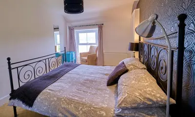 a bedroom with a bed with a lamp and a chair at Beacon Crag in Porthleven