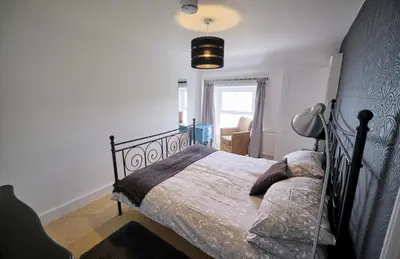 a bedroom with a bed and a lamp and a window at Beacon Crag in Porthleven