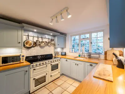 a large kitchen with white appliances and blue cabinets at Holiday Home Hillside by Interhome in Portloe