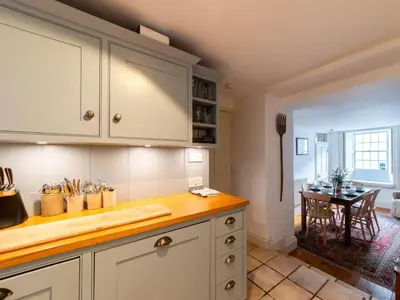 a kitchen with white cabinets and a wooden counter top at Holiday Home Hillside by Interhome in Portloe