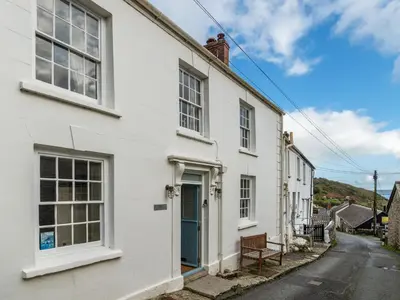 a white house with a blue door on a street at Holiday Home Hillside by Interhome in Portloe
