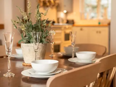 a wooden table with plates and bowls and glasses on it at Holiday Home Hillside by Interhome in Portloe