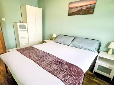 a bedroom with a white bed and a dresser at Chalet Kingfishers Lodge by Interhome in Liskeard