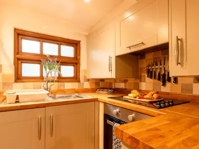 a kitchen with white cabinets and a counter top at Holiday Home Piskey Cottage by Interhome in Mevagissey