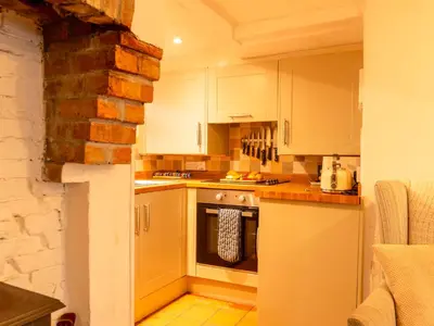 a kitchen with white cabinets and an oven at Holiday Home Piskey Cottage by Interhome in Mevagissey