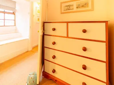 a chest of draws in a room with a window at Holiday Home Piskey Cottage by Interhome in Mevagissey