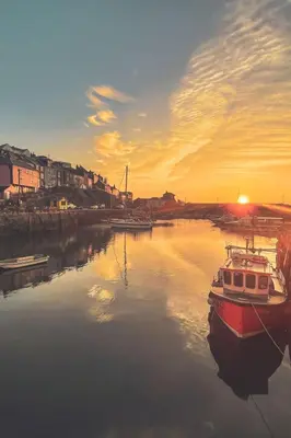 a boat is docked in the water at sunset at Holiday Home Piskey Cottage by Interhome in Mevagissey