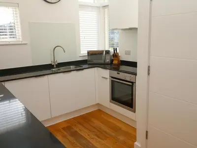 a white kitchen with a sink and a microwave at Una, Lodge 70 in St Ives