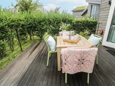 a wooden table and chairs on a deck at Una, Lodge 70 in St Ives