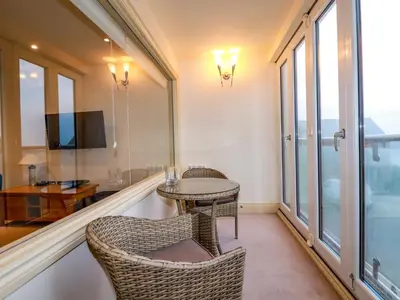 a balcony with two chairs and a table and a television at Blue Horizon in Port Isaac