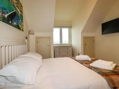 a bedroom with a white bed and a window at Blue Horizon in Port Isaac