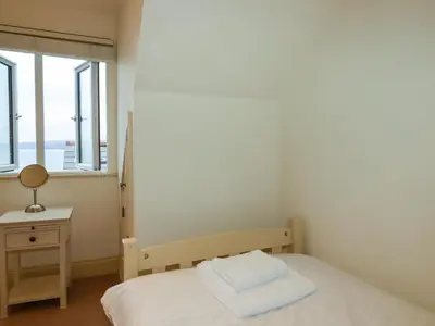 a small bedroom with a bed and a window at Blue Horizon in Port Isaac
