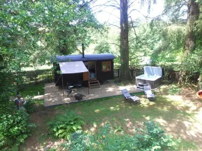 a small house with a blue roof in a yard at Waters Meet in Warleggan
