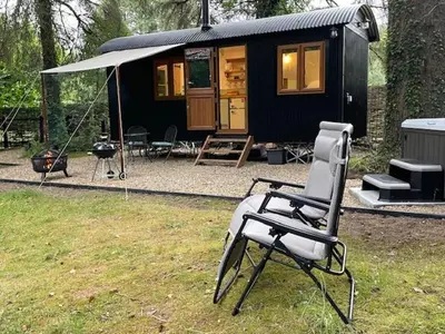 a chair sitting in front of a tiny house at Waters Meet in Warleggan