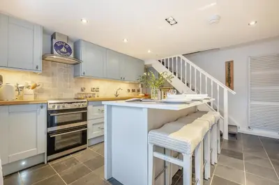 a kitchen with white cabinets and a counter with stools at 2 Bed in Fowey oc-r30265 in Fowey