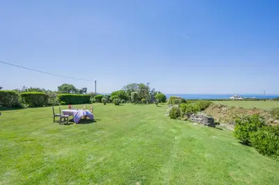 a picnic table in a field with the ocean in the background at 4 Bed in Trevillick oc-m30376 in Tintagel