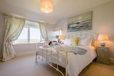 a bedroom with a white bed with a dog sitting on it at 4 Bed in Trevillick oc-m30376 in Tintagel