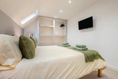 a white bedroom with a bed with a tv on the wall at 2 Bed in Padstow oc-t30497 in Padstow