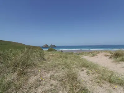 a sandy beach with grass and the ocean in the background at Atlantic View in Newquay