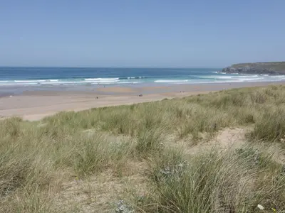 a beach with people walking on the sand and the ocean at Atlantic View in Newquay
