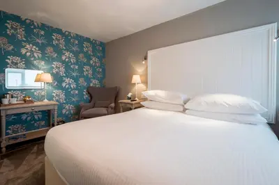 a bedroom with a large white bed and a chair at The Gannet Inn in St Ives