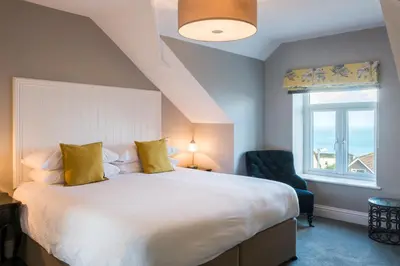 a bedroom with a bed and a chair and a window at The Gannet Inn in St Ives