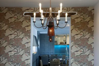 a chandelier in a dining room with floral wallpaper at The Gannet Inn in St Ives
