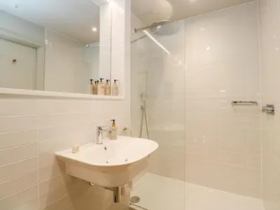 a white bathroom with a sink and a shower at Villa 80 in St Ives