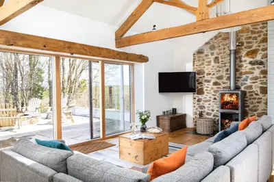a living room with a couch and a fireplace at Songbirds in Bude