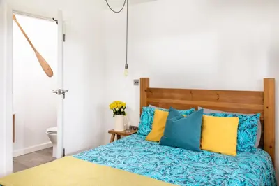 a bedroom with a bed with blue and yellow pillows at Songbirds in Bude