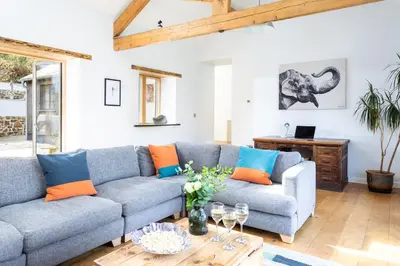 a living room with a blue couch and orange pillows at Songbirds in Bude