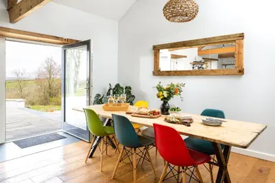 a dining room with a wooden table and colorful chairs at Songbirds in Bude