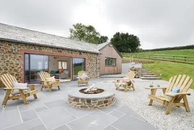 a patio with chairs and a fire pit at Songbirds in Bude