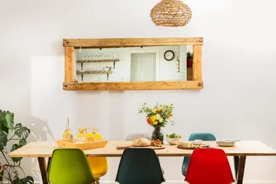 a dining room table with colorful chairs and a mirror at Songbirds in Bude