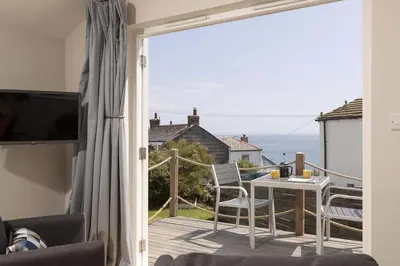 a room with a balcony with a table and chairs at Stylish Boatshed with Sea Views Private Parking in Gorran Haven