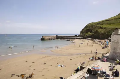a group of people on a beach near the ocean at Stylish Boatshed with Sea Views Private Parking in Gorran Haven