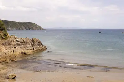 a view of a beach with a boat in the water at Stylish Boatshed with Sea Views Private Parking in Gorran Haven
