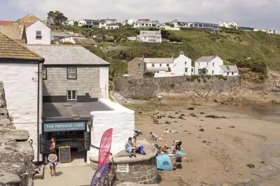 a group of people sitting on a beach at Stylish Boatshed with Sea Views Private Parking in Gorran Haven
