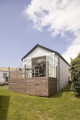 a small house with a large window on the side of it at Stylish Boatshed with Sea Views Private Parking in Gorran Haven