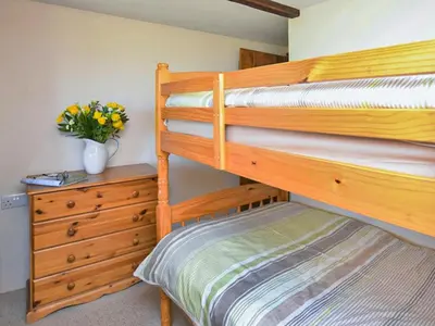 a bedroom with two bunk beds and a dresser at Miller's Cottage -Uk48595 in Warbstow