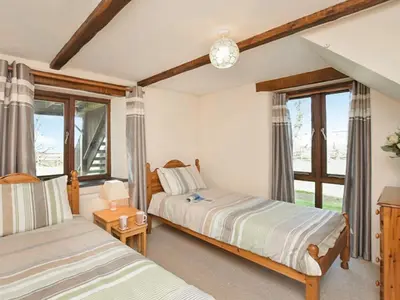a bedroom with two beds and windows in it at Miller's Cottage -Uk48595 in Warbstow