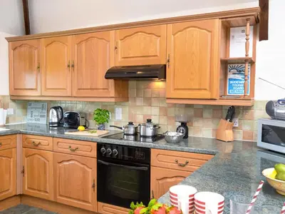 a kitchen with wooden cabinets and a stove top oven at Miller's Cottage -Uk48595 in Warbstow