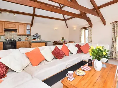 a living room with a white couch and a wooden table at Miller's Cottage -Uk48595 in Warbstow