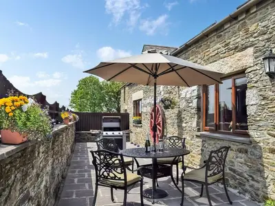 a table and chairs with an umbrella on a patio at Bill And Ben's Cottage - Uk48619 in Warbstow