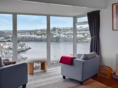 a living room with a large window with a view of the water at Pencarrow in Fowey