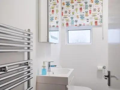 a white bathroom with a sink and a mirror at Pencarrow in Fowey