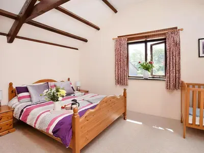 a bedroom with a wooden bed and a window at Grandma's Cottage - Uk48618 in Warbstow