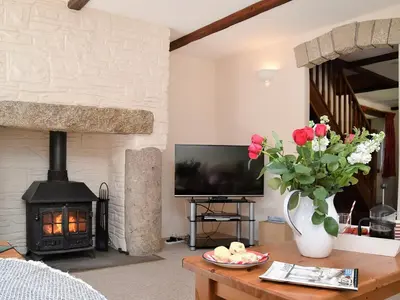 a living room with a fireplace and a table with flowers at Grandma's Cottage - Uk48618 in Warbstow