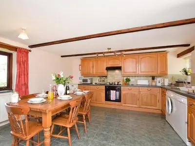 a kitchen with a wooden table and wooden cabinets at Grandma's Cottage - Uk48618 in Warbstow