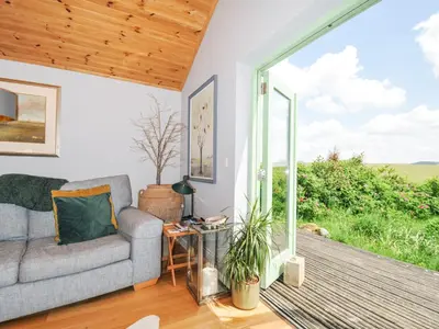 a living room with a couch and a large window at Smugglers in Bodmin